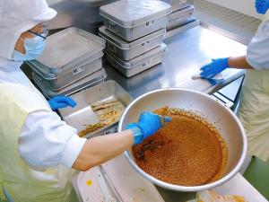 揚げたさんまにタレをくぐらせて配食します